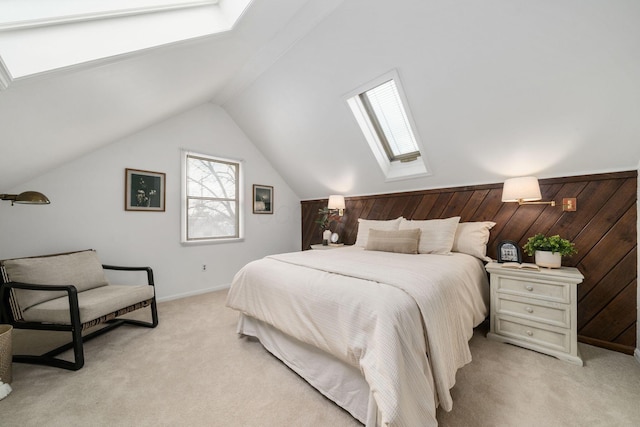 bedroom with vaulted ceiling with skylight, light colored carpet, and wooden walls