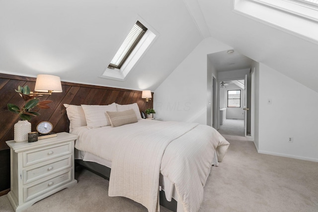 bedroom featuring baseboards, lofted ceiling with skylight, and light colored carpet