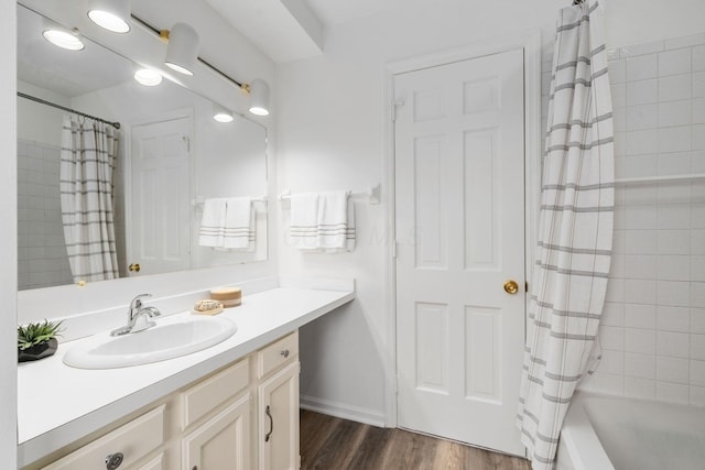 bathroom featuring shower / tub combo, wood finished floors, vanity, and baseboards