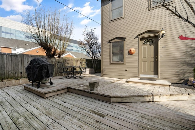 wooden terrace with outdoor dining area, fence, and grilling area