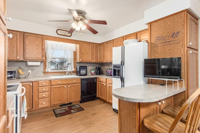 kitchen with a breakfast bar, sink, light hardwood / wood-style flooring, white appliances, and decorative backsplash