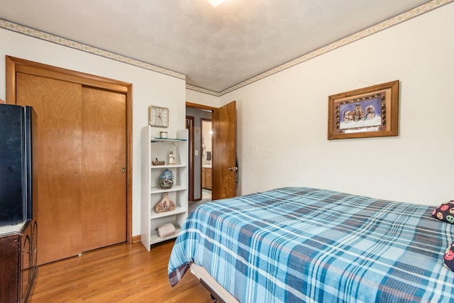 bedroom featuring ornamental molding, light wood-type flooring, and a closet