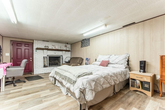 bedroom featuring hardwood / wood-style flooring and a brick fireplace