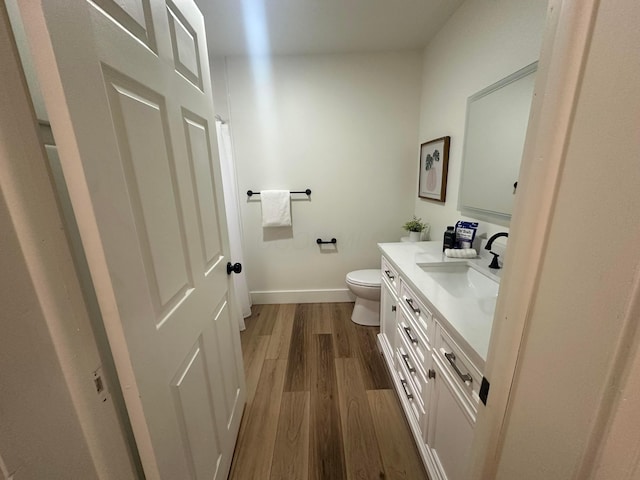 bathroom featuring wood-type flooring, toilet, and vanity