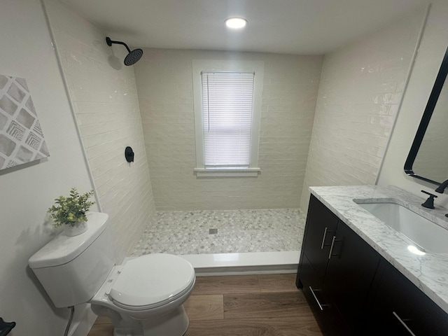 bathroom featuring tiled shower, vanity, toilet, and hardwood / wood-style floors