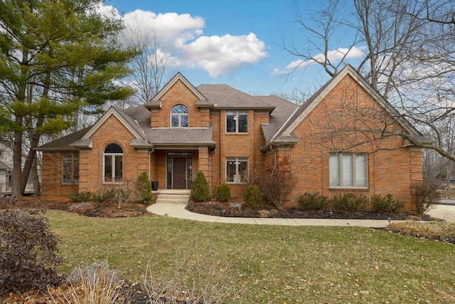 traditional home featuring a front lawn, brick siding, and roof with shingles