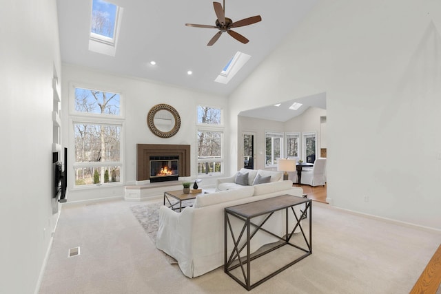 living room featuring baseboards, visible vents, high vaulted ceiling, light carpet, and a glass covered fireplace