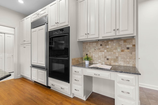 kitchen with built in desk, dark stone countertops, paneled fridge, and dobule oven black