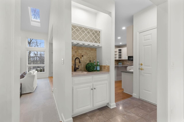 bar with baseboards, recessed lighting, a sink, decorative backsplash, and indoor wet bar