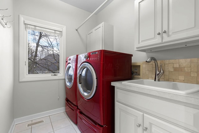 laundry room featuring washing machine and clothes dryer, visible vents, light tile patterned floors, cabinet space, and a sink