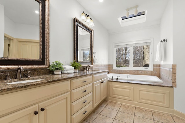 bathroom with a sink, a skylight, double vanity, and a bath