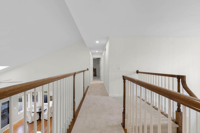 hall with an upstairs landing, recessed lighting, light colored carpet, and a skylight