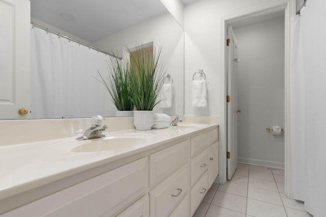 bathroom with tile patterned flooring, double vanity, baseboards, and a sink