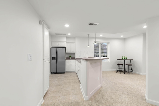 kitchen featuring visible vents, white cabinetry, recessed lighting, stainless steel fridge, and a peninsula