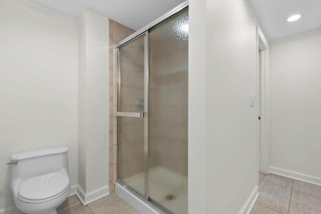 bathroom featuring tile patterned floors, baseboards, toilet, and a shower stall