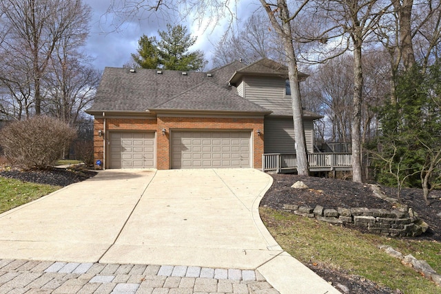 traditional-style house featuring driveway, an attached garage, brick siding, and roof with shingles