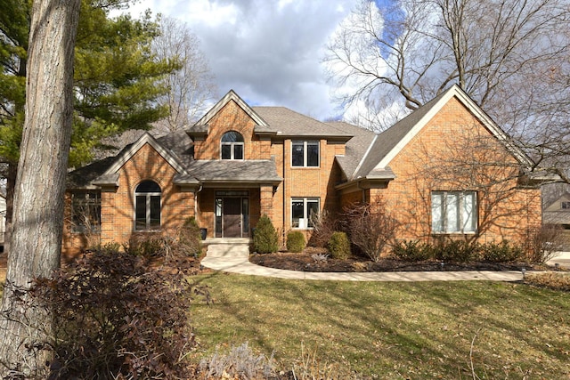 traditional home with a front yard, brick siding, and a shingled roof