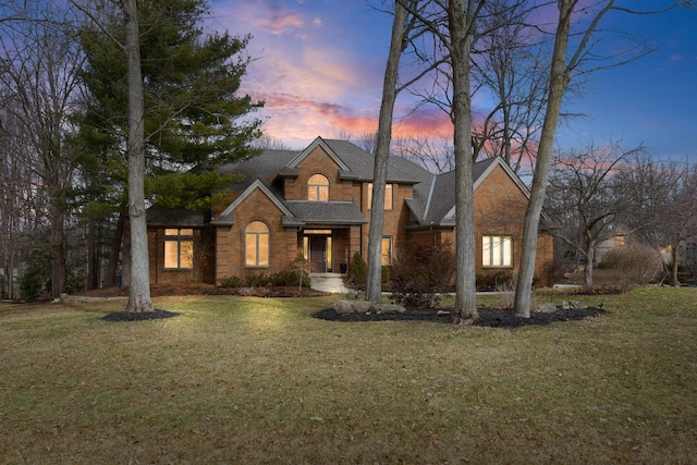 traditional-style home featuring a lawn and brick siding