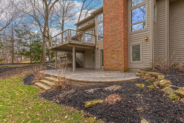 back of property with a deck, stairs, a patio area, and a chimney