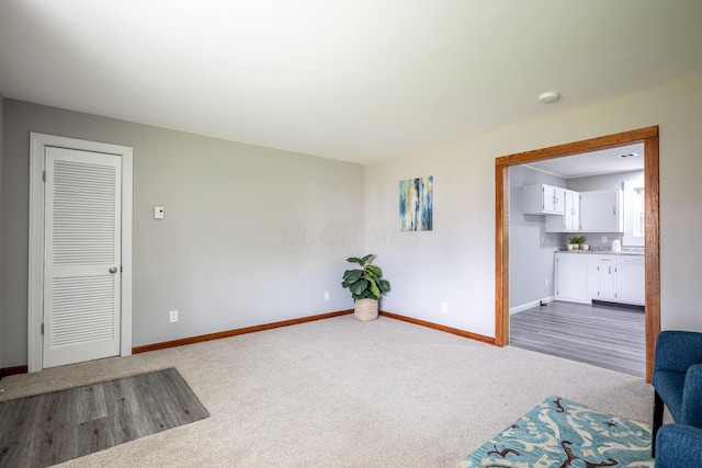 living area featuring dark carpet and baseboards