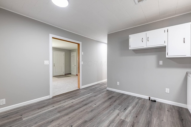 interior space with baseboards, crown molding, and wood finished floors