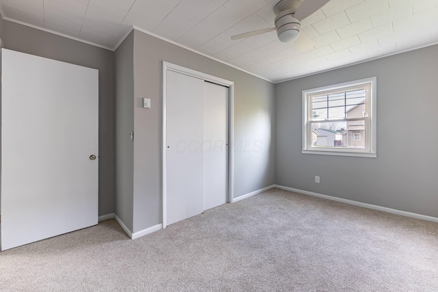 unfurnished bedroom featuring ceiling fan, carpet floors, a closet, and ornamental molding