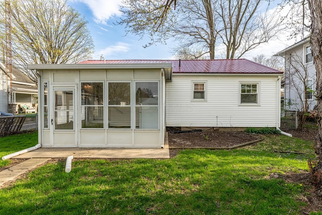 rear view of property with fence, a lawn, a sunroom, and metal roof