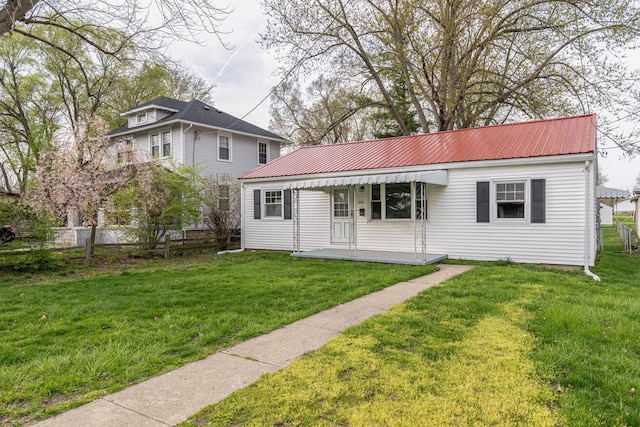 view of front of home with a front lawn, fence, and metal roof