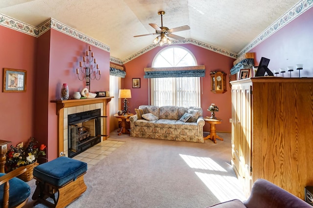 living room featuring lofted ceiling, a tile fireplace, ceiling fan, a textured ceiling, and light colored carpet