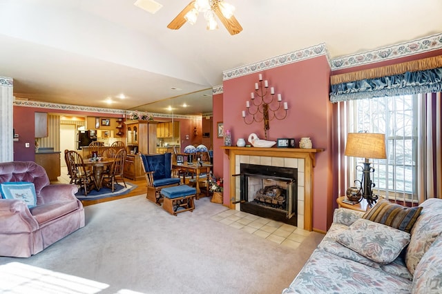 carpeted living room featuring vaulted ceiling, a tile fireplace, and ceiling fan