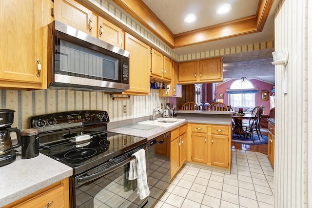 kitchen featuring sink, light tile patterned floors, black appliances, and a raised ceiling