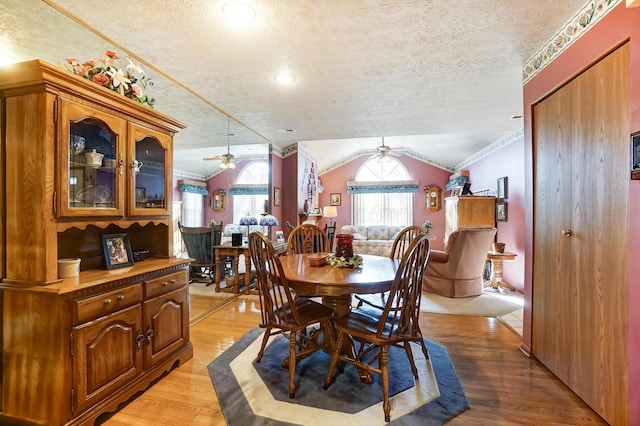 dining room featuring crown molding, lofted ceiling, a textured ceiling, and light wood-type flooring