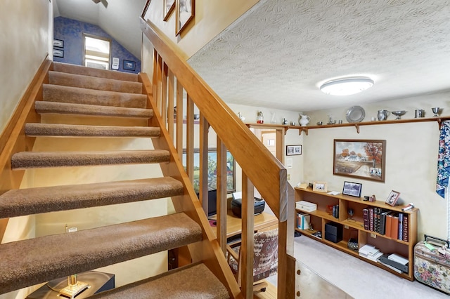 stairs featuring carpet flooring, vaulted ceiling, and a textured ceiling