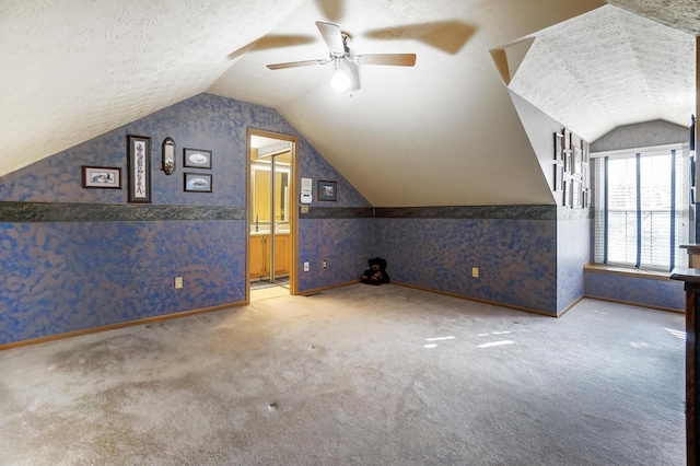 additional living space featuring ceiling fan, vaulted ceiling, a textured ceiling, and carpet