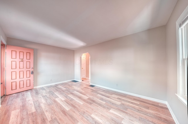 empty room with light wood-style flooring, visible vents, and baseboards