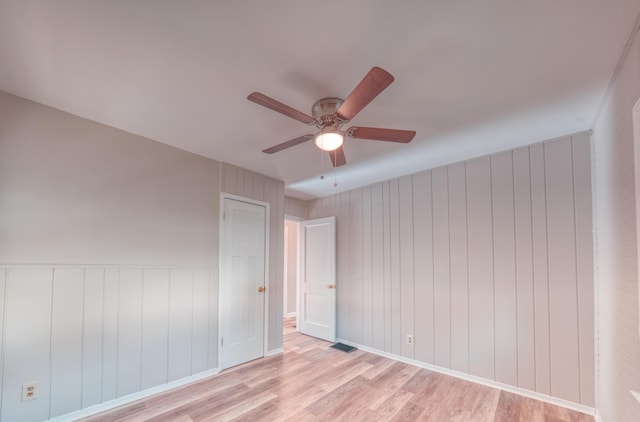 empty room featuring light wood-style flooring, a ceiling fan, and visible vents