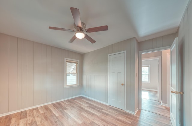 unfurnished bedroom with light wood-style flooring, baseboards, a closet, and ceiling fan