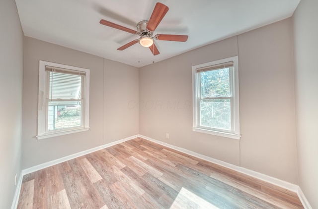 spare room featuring a wealth of natural light, light wood finished floors, and baseboards