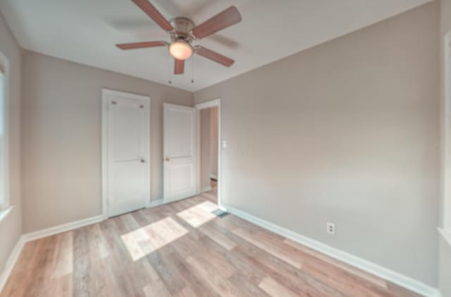 unfurnished bedroom with a ceiling fan, light wood-style floors, and baseboards