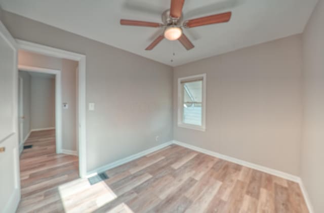 empty room with light wood finished floors, baseboards, and ceiling fan