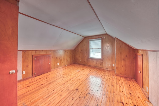 bonus room with hardwood / wood-style floors, vaulted ceiling, and wood walls