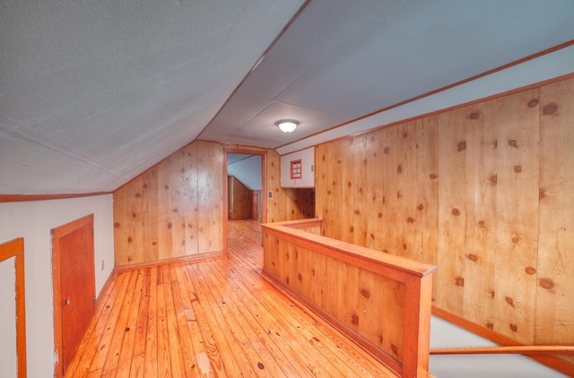 bonus room featuring wood-type flooring, wooden walls, and vaulted ceiling