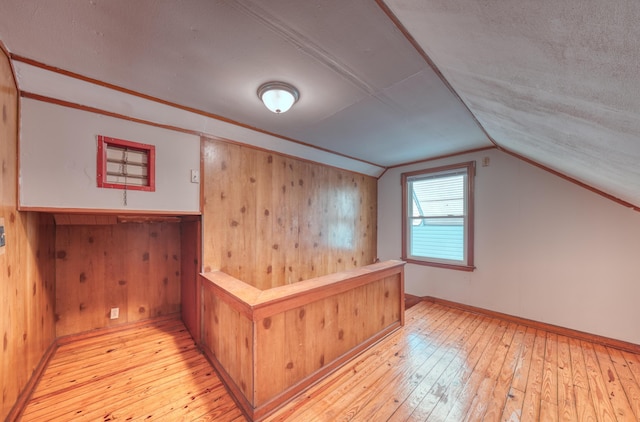 bar featuring wooden walls, baseboards, lofted ceiling, and wood-type flooring