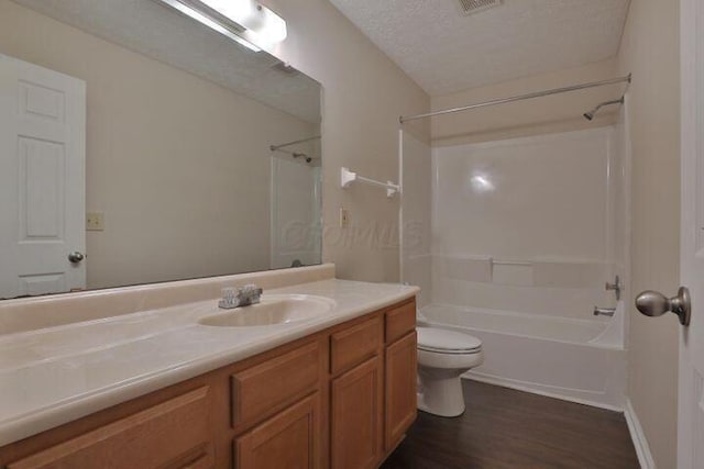 full bathroom featuring hardwood / wood-style flooring, shower / tub combination, vanity, a textured ceiling, and toilet