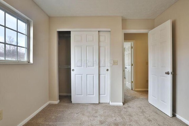 unfurnished bedroom with light carpet and a closet