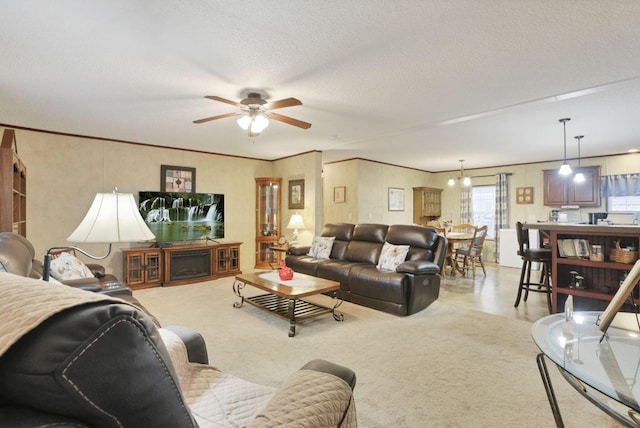 living room with ceiling fan, crown molding, and a textured ceiling