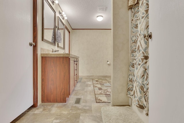 bathroom with crown molding, vanity, a shower with shower curtain, and a textured ceiling