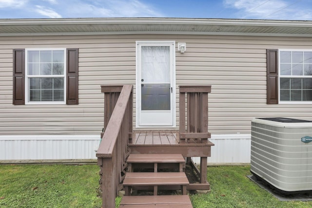 doorway to property with central AC and a lawn