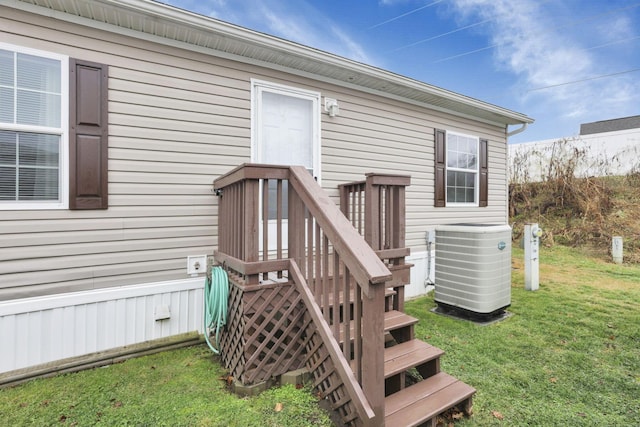 entrance to property featuring central AC unit and a lawn