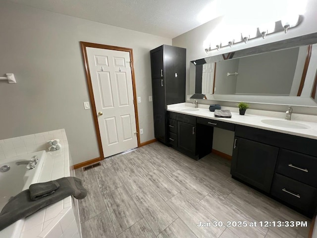 bathroom with vanity, a tub, and a textured ceiling